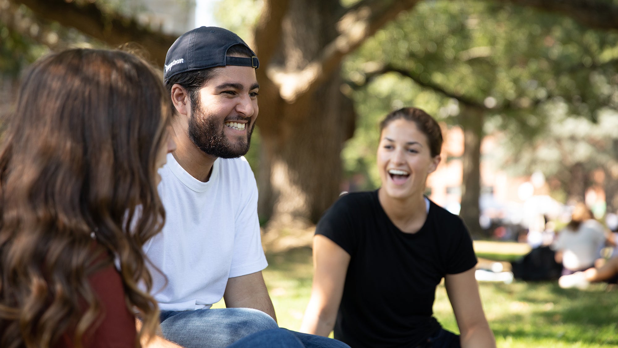 Undergraduate students sitting on healy lawn at Georgetown University laughing